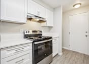 Thumbnail 26 of 40 - A kitchen with white cabinets and a black stove top oven.