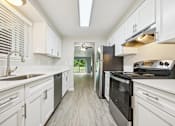 Thumbnail 27 of 40 - A modern kitchen with white cabinets and stainless steel appliances.