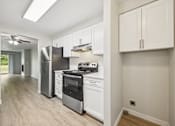 Thumbnail 28 of 40 - A kitchen with white cabinets and a stainless steel refrigerator.