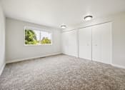 Thumbnail 29 of 40 - A room with white walls and a window showing greenery outside.