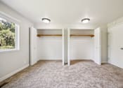Thumbnail 32 of 40 - A room with white walls and carpeted floor with two closets.