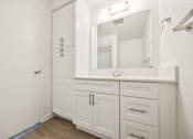 Thumbnail 34 of 40 - A white bathroom with a mirror and a cabinet.