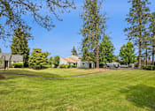 Thumbnail 10 of 40 - A large grassy area with trees and houses in the background.