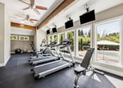 Thumbnail 12 of 40 - A gym with treadmills, a fan, and a view of a pool.