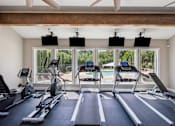 Thumbnail 11 of 40 - A gym with treadmills, exercise bikes, and a ceiling fan.