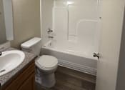 Thumbnail 10 of 18 - A white toilet sits next to a sink in a small bathroom.