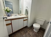 Thumbnail 13 of 56 - A white toilet sits in a bathroom next to a sink and a mirror.
