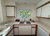 Thumbnail 9 of 56 - A kitchen with white cabinets and a window.