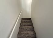 Thumbnail 12 of 56 - A staircase with a carpeted runner and white handrail.