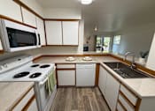 Thumbnail 19 of 56 - A kitchen with a stove top oven, microwave, dishwasher, and sink.