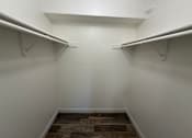 Thumbnail 23 of 56 - A walk in closet with a wooden floor and white walls.