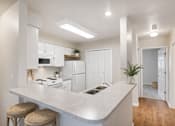 Thumbnail 3 of 35 - A kitchen with white cabinets and a countertop with two stools.