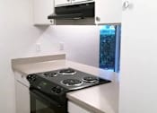 Thumbnail 37 of 40 - A black stove top oven with four burners and a silver oven door sits on a white countertop.
