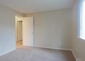 Thumbnail 62 of 64 - A room with a carpeted floor and a doorway leading to another room.