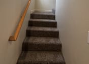 Thumbnail 8 of 18 - A staircase with a wooden handrail and carpeted steps.