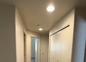 Thumbnail 9 of 18 - A hallway with white walls and a carpeted floor.