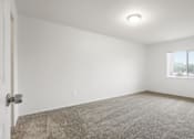 Thumbnail 9 of 12 - A room with a carpeted floor, a door, and a window.