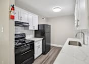 Thumbnail 16 of 27 - A kitchen with black appliances and white cabinets.