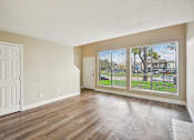 Thumbnail 17 of 27 - A room with a white door and a window with a view of a fence and a house.