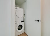 Thumbnail 16 of 81 - A white door opens to a small laundry room with a washer and dryer.