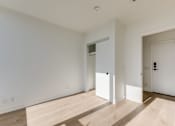 Thumbnail 74 of 81 - A room with white walls and wooden flooring with two doors.