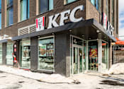 Thumbnail 2 of 81 - A KFC restaurant with a snowy sidewalk in front.