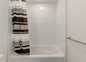 Thumbnail 61 of 81 - A white bathtub with a shower curtain in a bathroom.