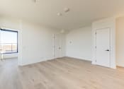 Thumbnail 54 of 81 - A room with white walls and wooden flooring with a door on the right.