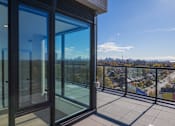 Thumbnail 48 of 81 - A balcony with glass doors overlooking a cityscape.