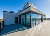 Thumbnail 47 of 81 - A modern building with a flat roof and large glass windows.