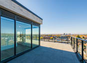 Thumbnail 45 of 81 - A balcony with glass doors overlooking a cityscape.