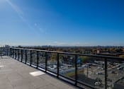 Thumbnail 42 of 81 - A balcony with a view of a parking lot and buildings.