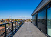 Thumbnail 39 of 81 - A balcony with a view of a cityscape and a tower in the distance.