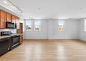 Thumbnail 18 of 20 - A kitchen with wooden cabinets and black appliances.