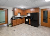 Thumbnail 8 of 20 - A kitchen with black appliances and wooden cabinets.