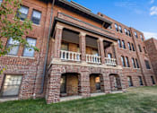 Thumbnail 3 of 20 - A red brick building with a balcony in the middle.