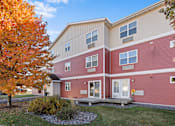 Thumbnail 6 of 9 - A red building with a tree in front of it.