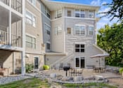 Thumbnail 13 of 59 - A modern apartment building with a patio and outdoor furniture.