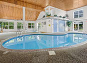 Thumbnail 12 of 59 - A large indoor swimming pool with a wooden ceiling.