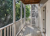 Thumbnail 9 of 59 - A wooden deck with a railing and a view of trees and a building in the background.