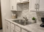 Thumbnail 29 of 39 - A kitchen with white cabinets and a marble countertop.