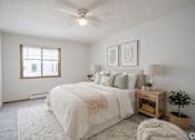 Thumbnail 26 of 39 - A bedroom with a large bed, a window, and a ceiling fan.
