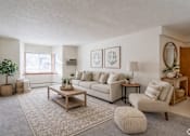 Thumbnail 22 of 39 - A living room with a white couch, a coffee table, and a rug.