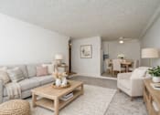 Thumbnail 17 of 39 - A living room with a grey couch, a wooden coffee table, and a white rug.
