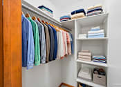 Thumbnail 10 of 39 - A closet with a variety of shirts and towels.