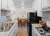 Thumbnail 8 of 39 - A kitchen with a black refrigerator, white cabinets, and a marble countertop.