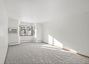 Thumbnail 18 of 39 - A large empty room with a window and a carpet on the floor.