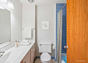 Thumbnail 23 of 39 - A white toilet sits in a bathroom next to a white sink.