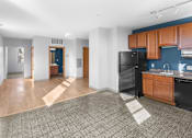 Thumbnail 11 of 20 - A kitchen area with a black refrigerator and wooden cabinets.