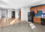 Thumbnail 13 of 20 - a living room with a kitchen and a black refrigerator